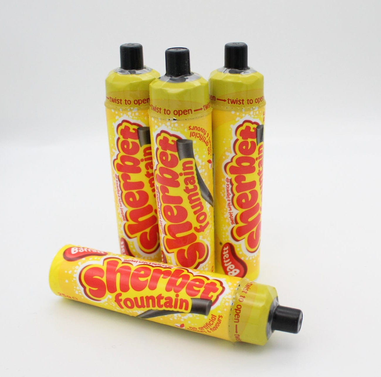 Four yellow plastic tubes of Sherbet Fountain candy with black caps on a white background.