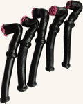 A group of soft liquorice pipes with pink sprinkles on the end, arranged in a line against a white background.