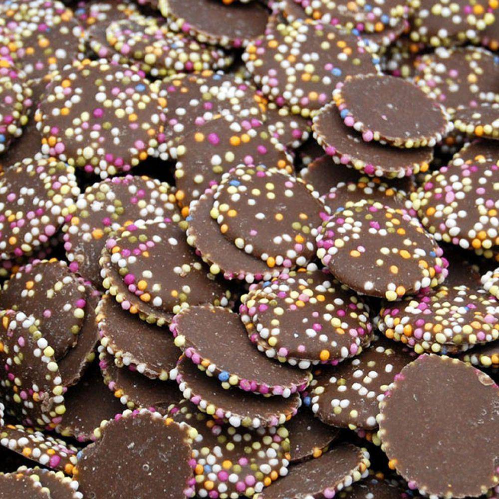 A close-up of chocolate jazzies, which are milk chocolate-flavored discs covered in bright candy sprinkles.